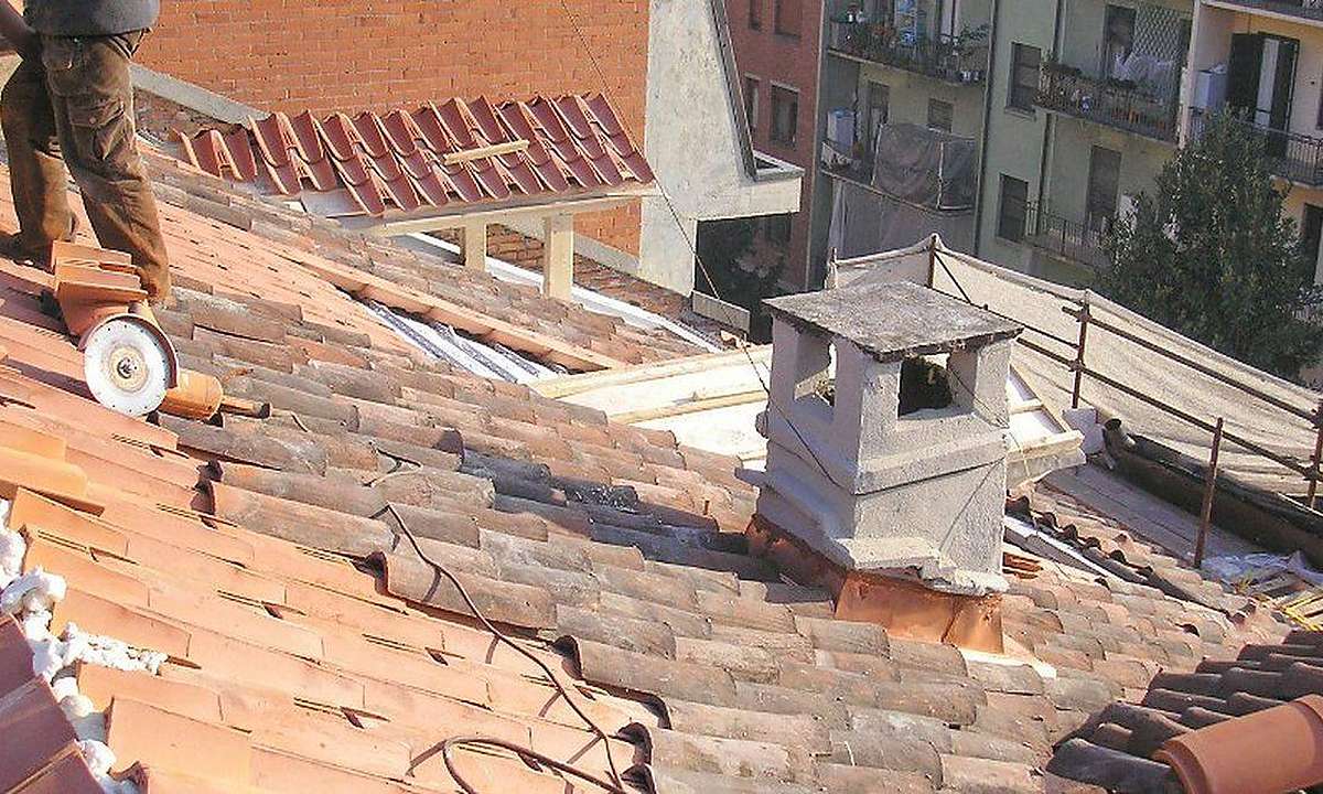 Chimenea de obra en un tejado de teja vieja durante una reparación