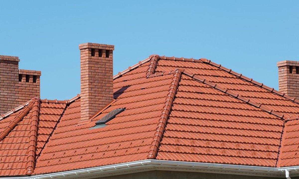 Vivienda con cubierta de teja a cuatro aguas, chimeneas y claraboyas