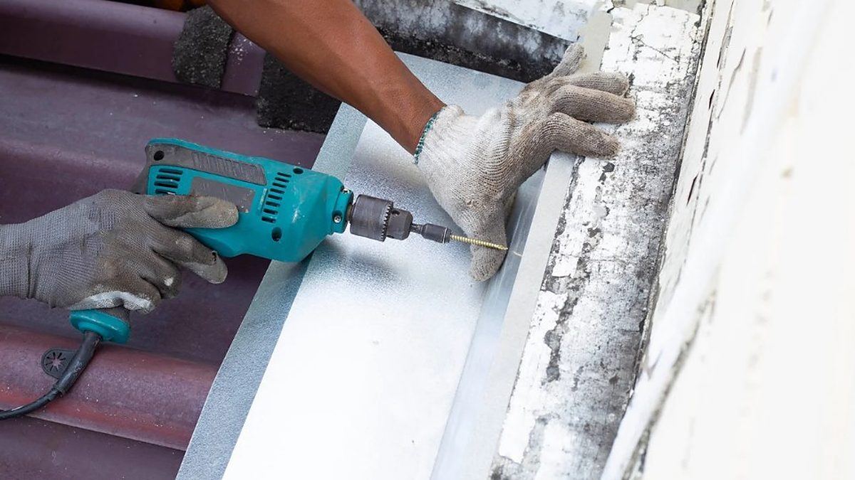 Montaje del canalón de zinc atornillado al alero de una vivienda de Vilalba